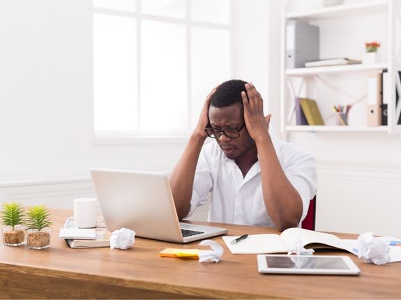 A man is feeling anxious and stressed because his work is not perfect. Perfectionism is a common compulsion for people suffering with OCD. OptimalLife Wellness can help.